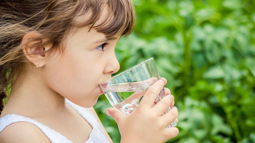 Mädchen trinkt aus Wasserglas.