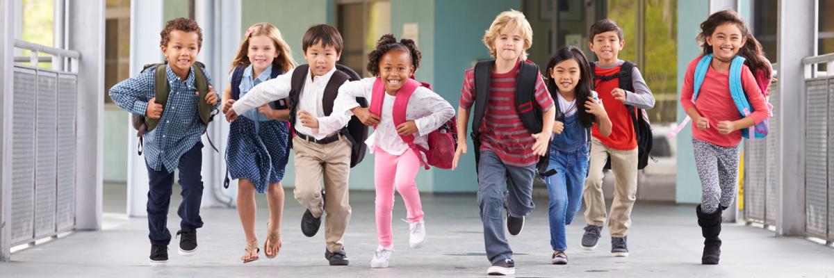 Eine Gruppe von Schulkindern rennt über den Schulhof