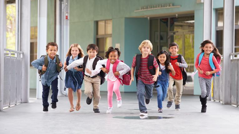 Eine Gruppe von Schulkindern rennt über den Schulhof