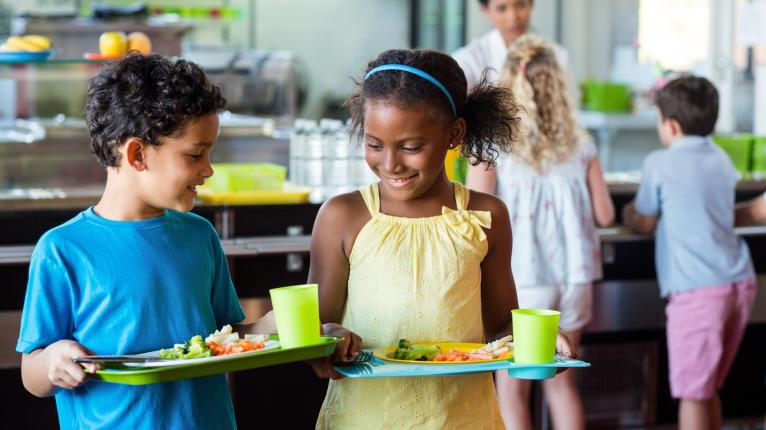 Zwei Schulkinder holen sich ihr Mittagessen und Getränk